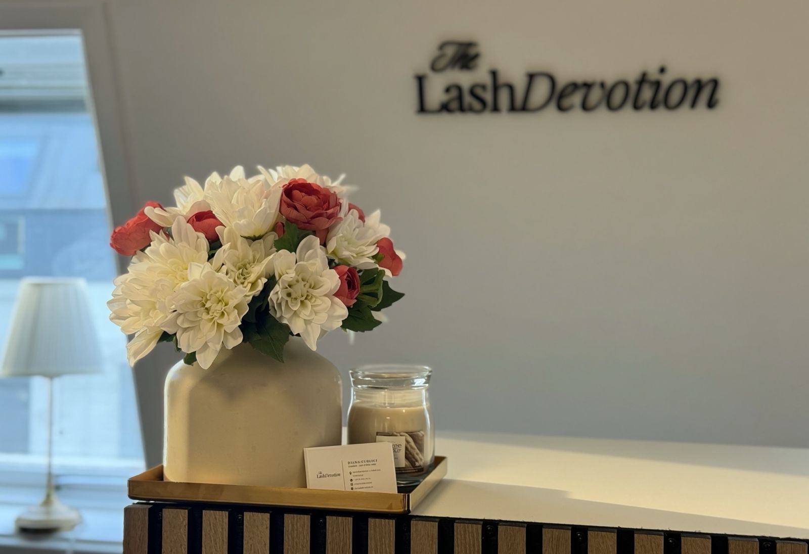 Reception med blommor och The Lash Devotions vägglogotyp